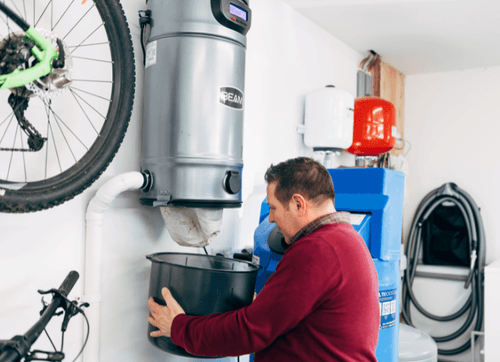Technician emptying a central vacuum bin