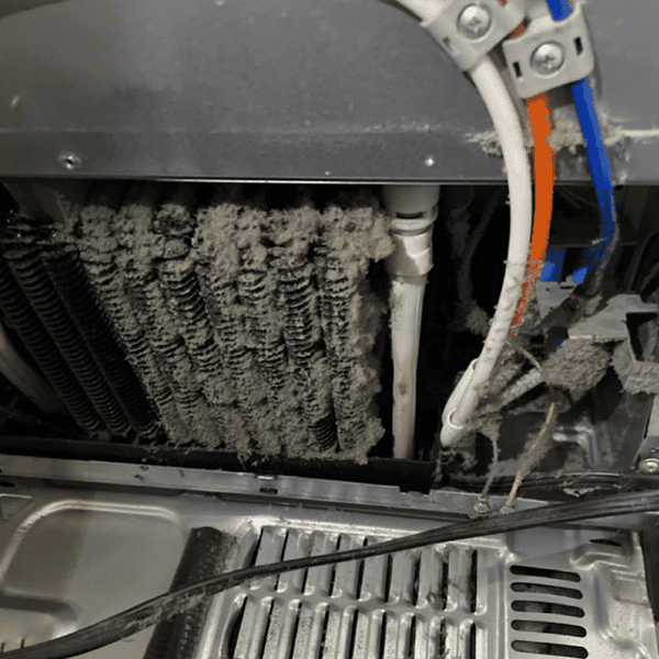 Dusty refrigerator condenser coils being cleaned
