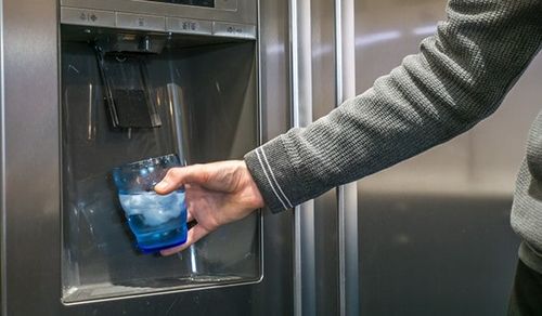 Glass being filled from a refrigerator water dispenser
